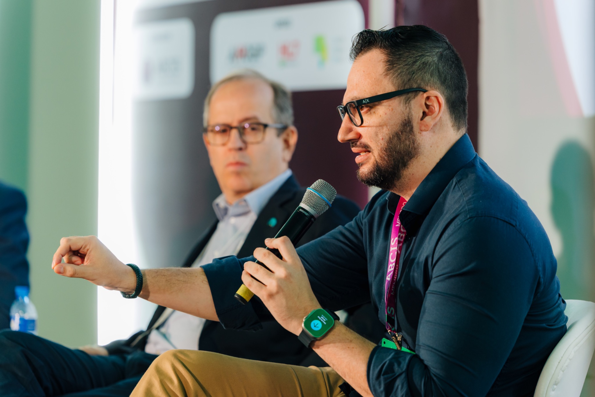 Alex Vieira participando de um painel e falando ao microfone